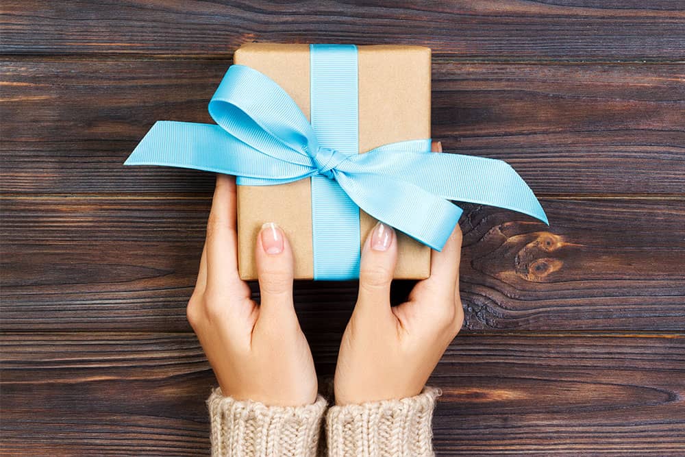 Woman holding a gift box with a blue ribbon