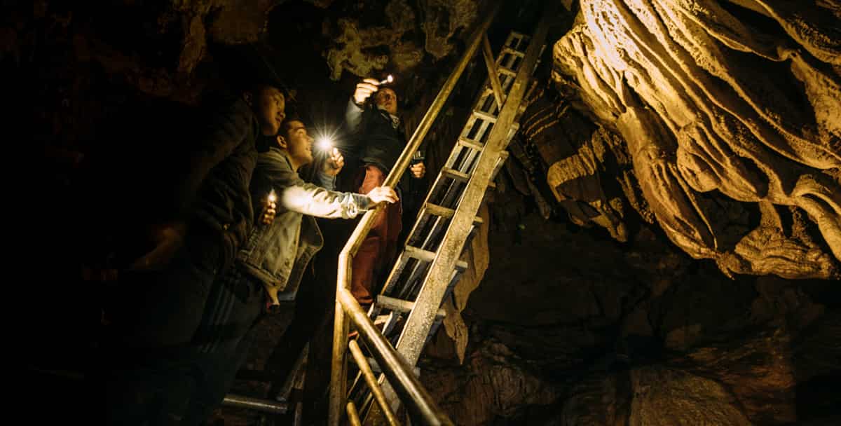 Three people on a staircase in a cave